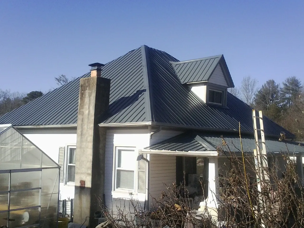 Dark blue standing seam metal roof on a white farmhouse with dormer — Slate & Tile Roof Repair by Roofing Brothers in Pearson