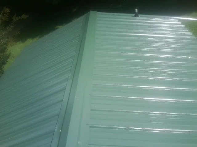 New green metal panels meeting at the ridge of a roof — Flat Roof Repair work by our crew in Pearson