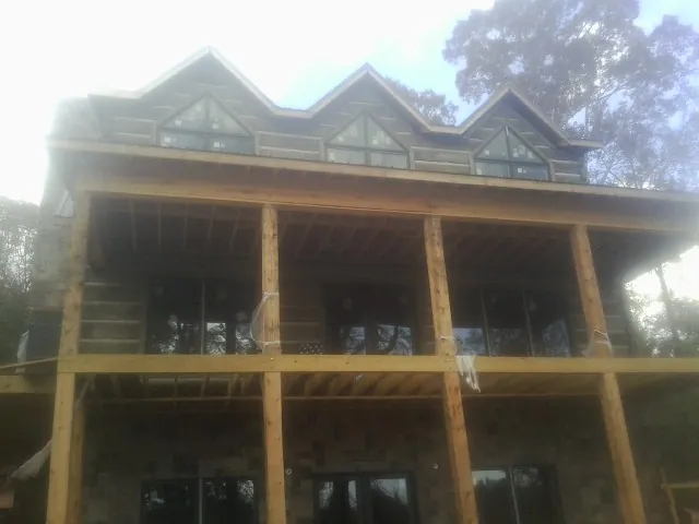 Dormers and porch framing on a large log home under construction — Roof Coating work by our crew in Pearson