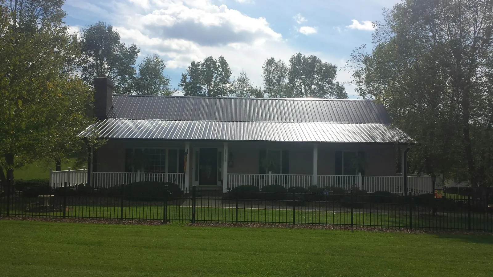 Gray metal roof on a brick ranch with a full width front porch — Gutter Guard Installation work by our crew in Pearson