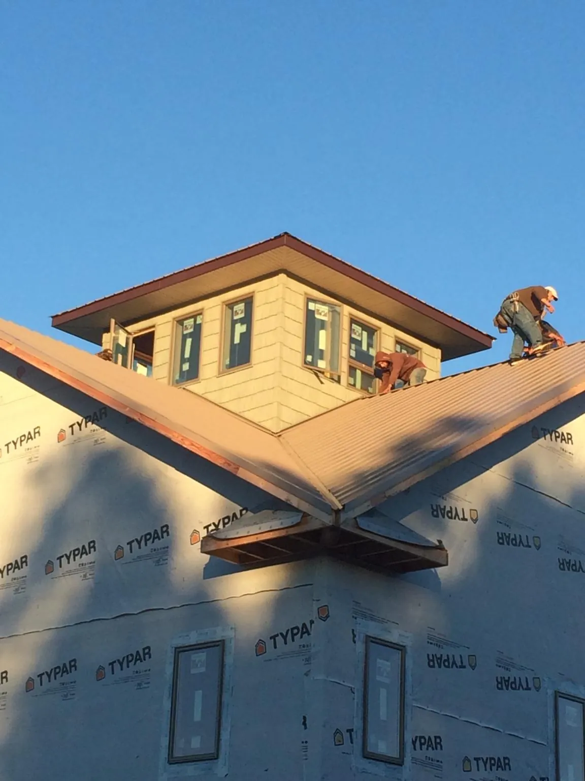 Roofers working around a rooftop cupola on a new metal roof at sunset — Roof Waterproofing in Pearson by Roofing Brothers